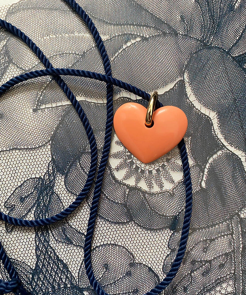 Coral heart pendant on a navy cord necklace. 